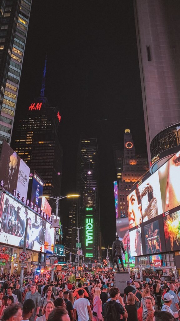 Crowds walking through Times Square at night under illuminated billboards.