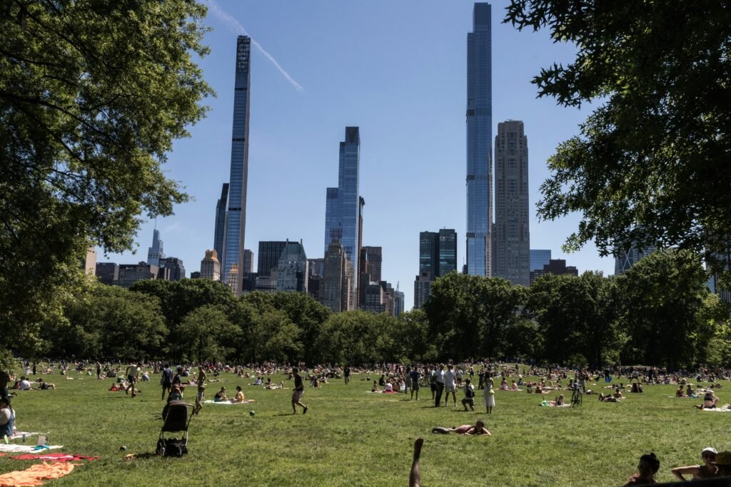 People relaxing on the grass at Sheep Meadow with the Manhattan skyline in the background